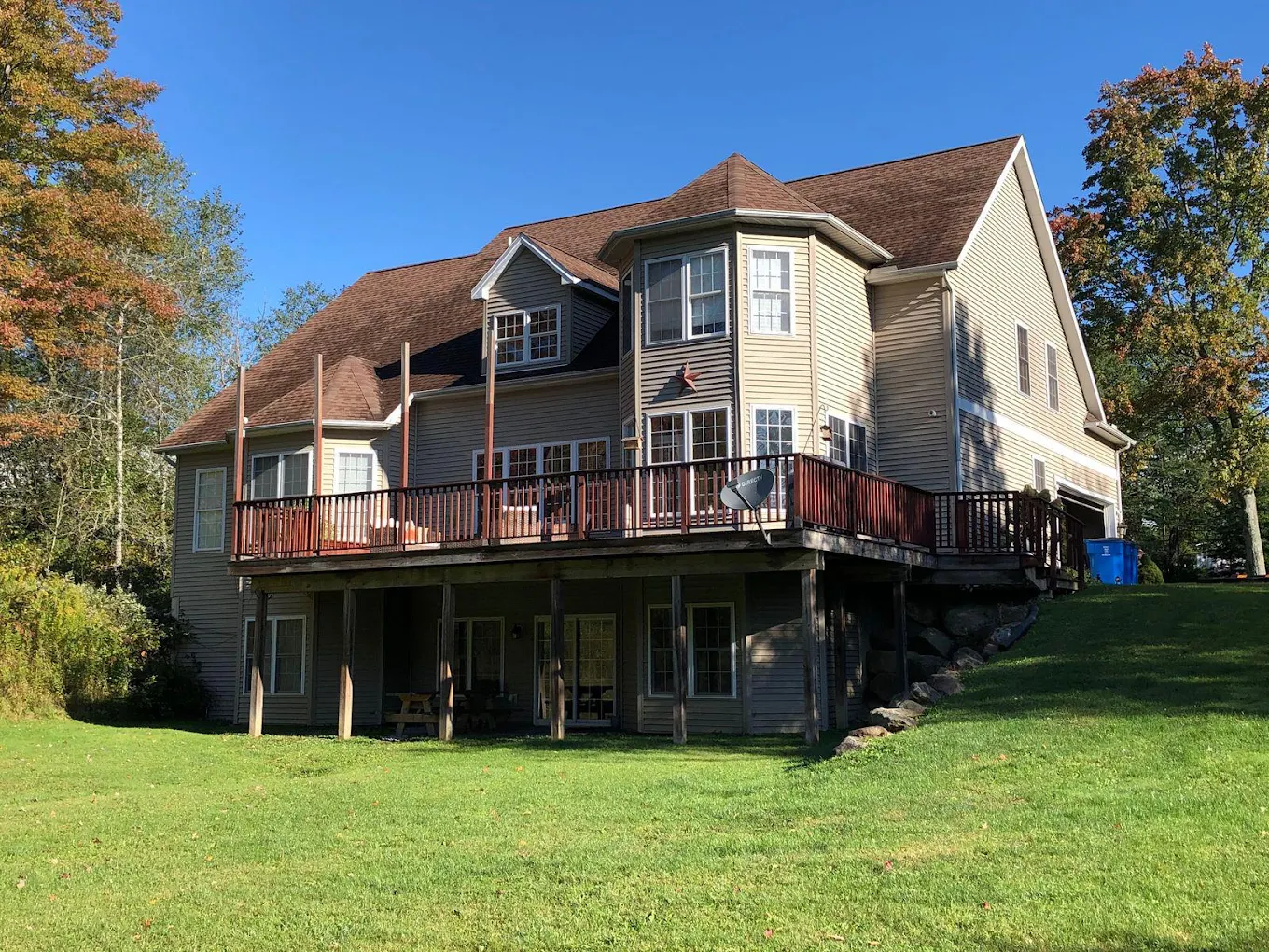 Rear view of residential facility with large deck and lawn