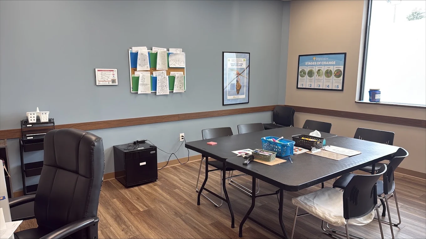 Group counseling room at BrightView Health Marion with large rectangular table, black chairs, activity materials, recovery-themed wall displays, and natural light