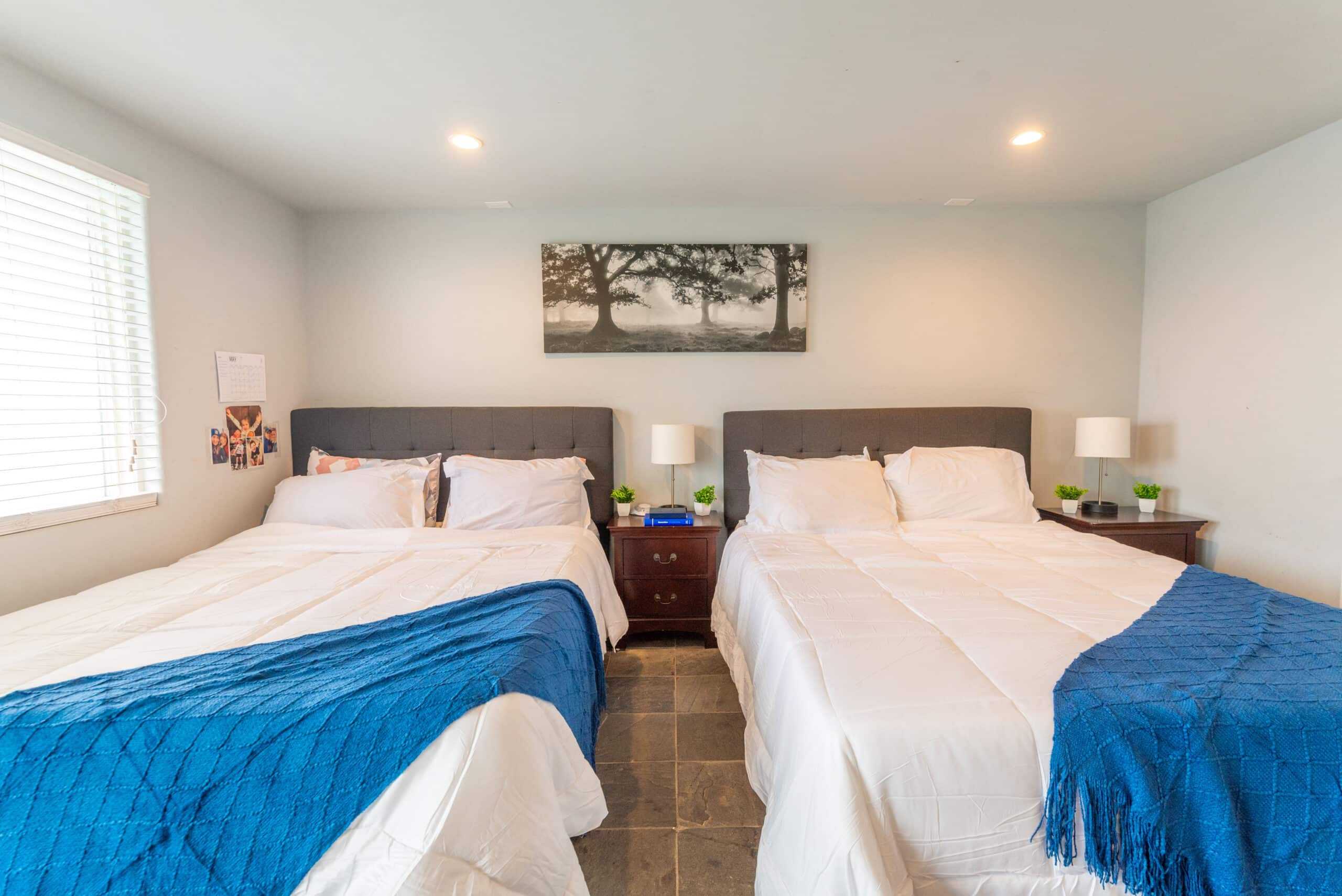 Two queen beds with white bedding and blue throws