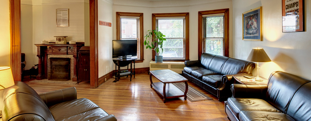 Spacious lounge with leather sofas, TV, and wood floors