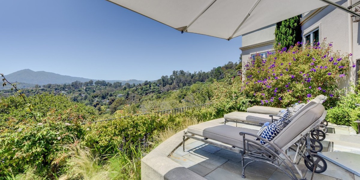 Scenic hillside view with lounge chairs and umbrella.