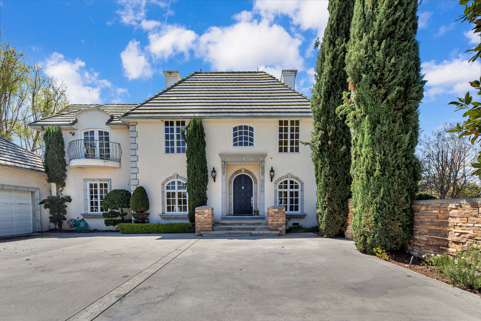 Large facility entrance with tall trees and arched front door