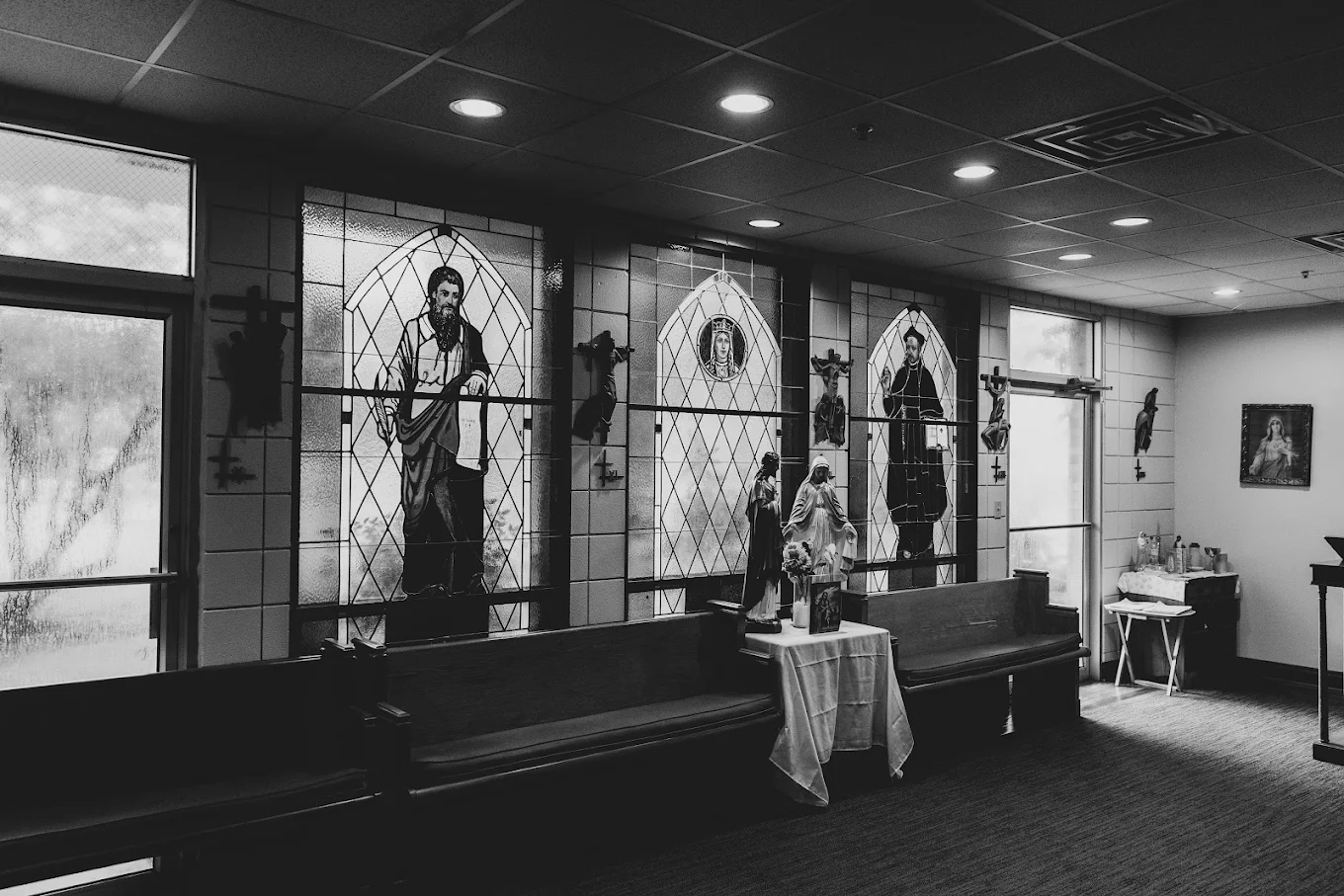 Quiet chapel with stained-glass windows, religious statues, and pew seating at NOLA Detox