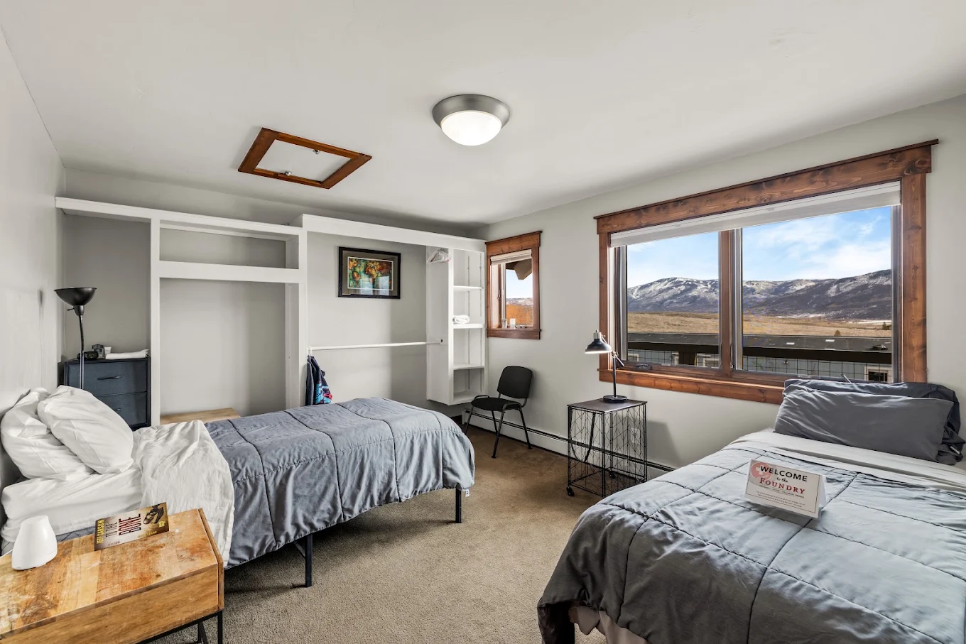Shared bedroom with two twin beds, built-in storage, and a large window overlooking the mountains
