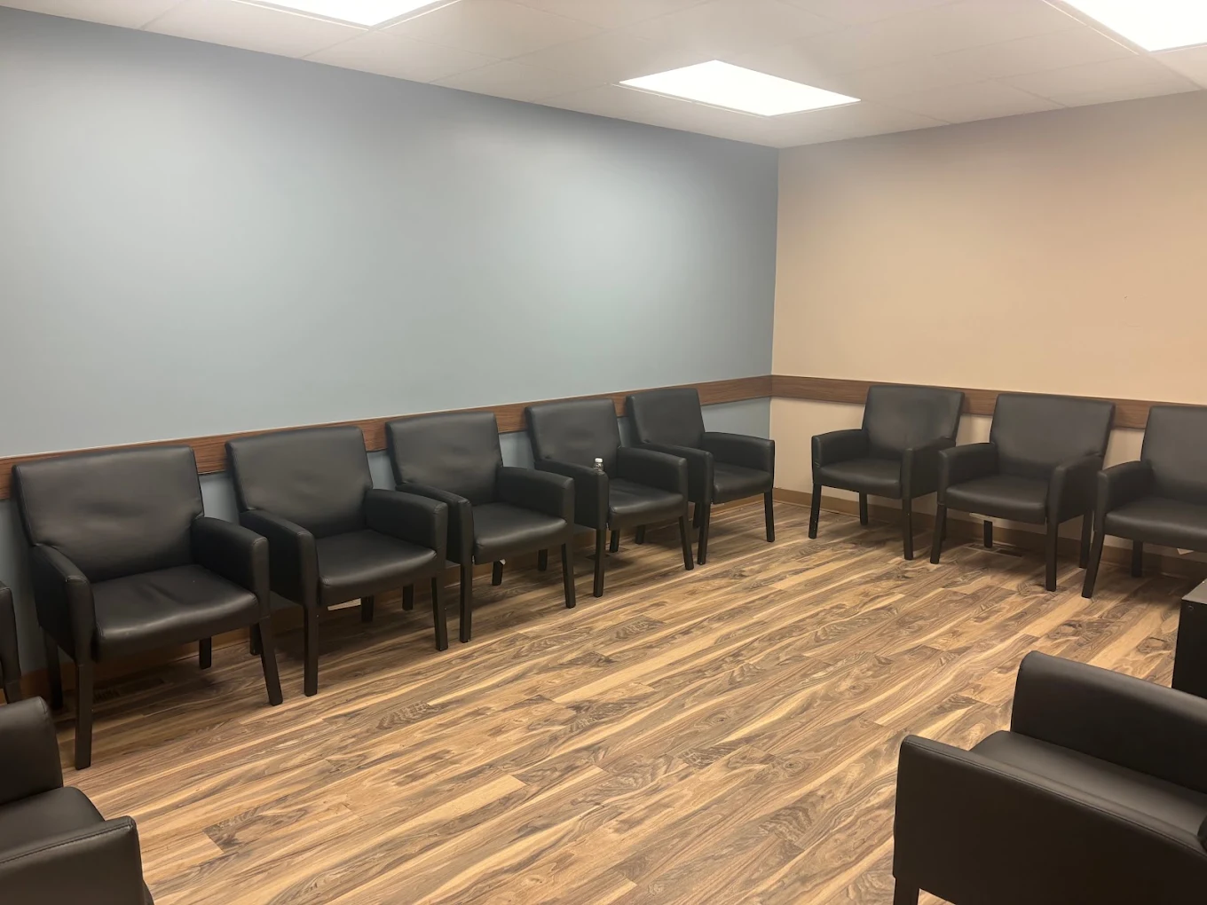 BrightView Akron waiting area with black armchairs, blue accent wall, wood-look flooring, and overhead lighting