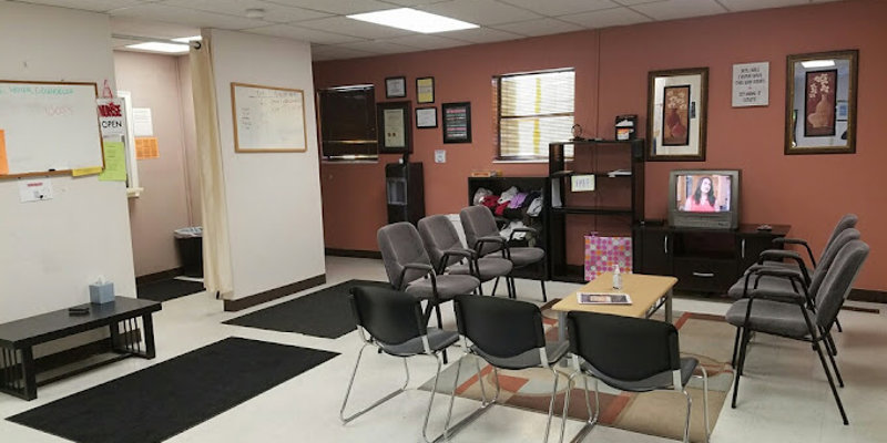 A welcoming waiting area features comfortable chairs, warm lighting, framed artwork, and a television, creating a calm and inviting space.