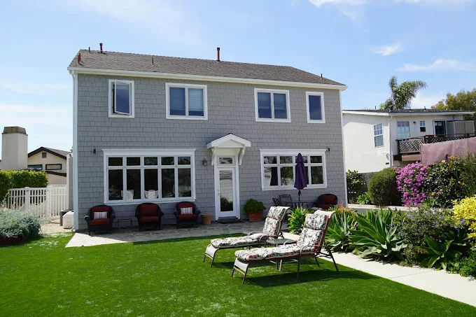 Two-story house with patio chairs and garden space
