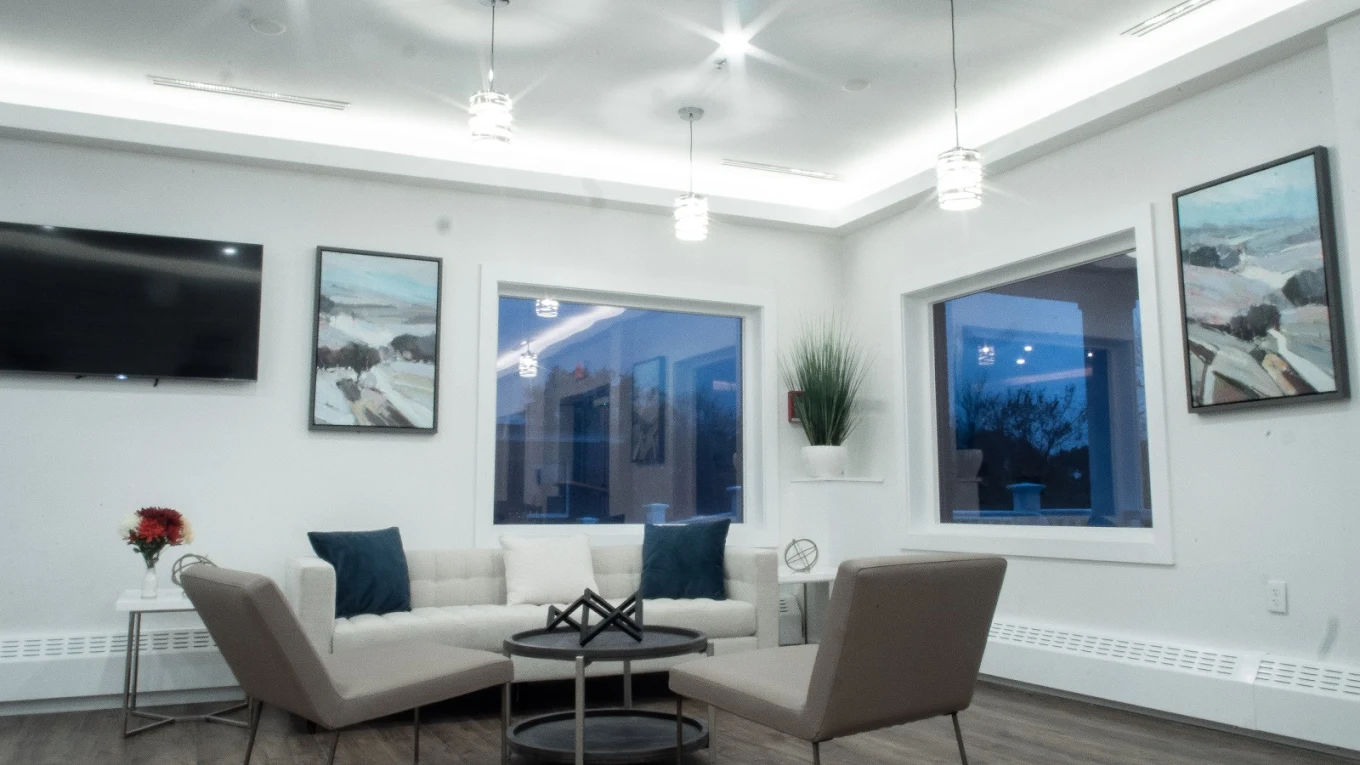 Sleek lounge with contemporary furniture, wall-mounted TV, and large windows at Evoke Wellness