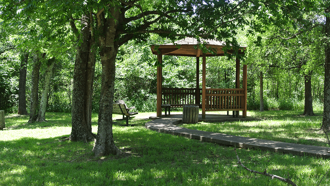 Shaded gazebo surrounded by trees and walking paths