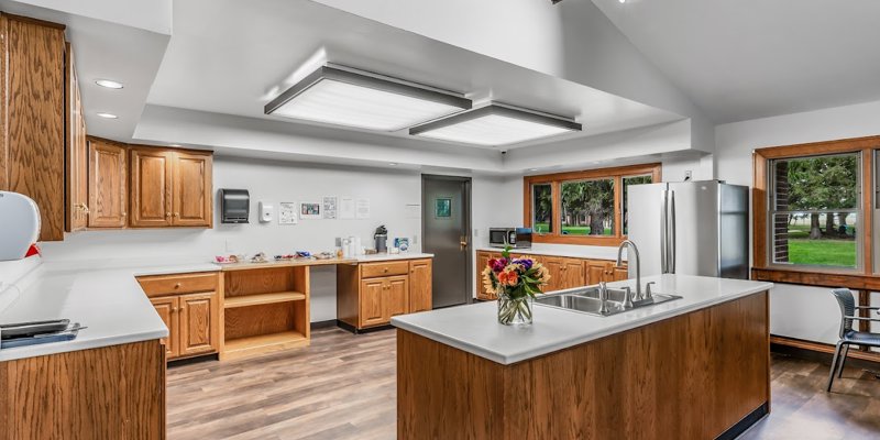 Spacious kitchen with warm wood cabinetry, modern appliances, large windows, and a central island, creating an inviting and functional space.