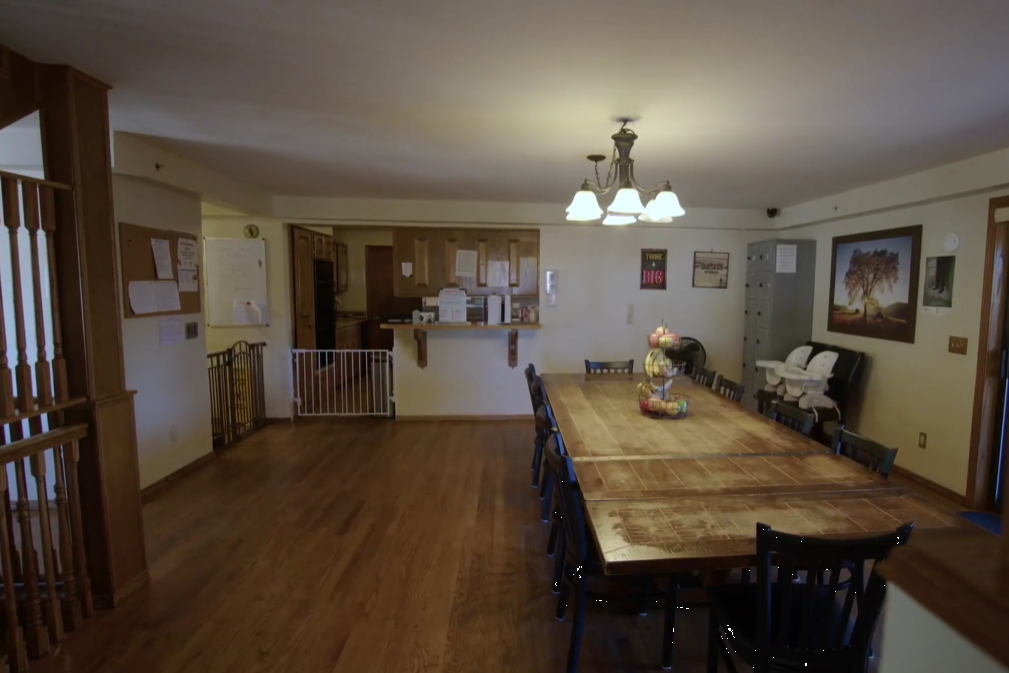 Large dining table and chairs near open kitchen with wooden floors