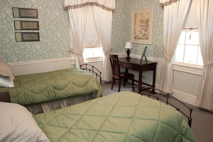 Two twin beds with green bedding and a desk
