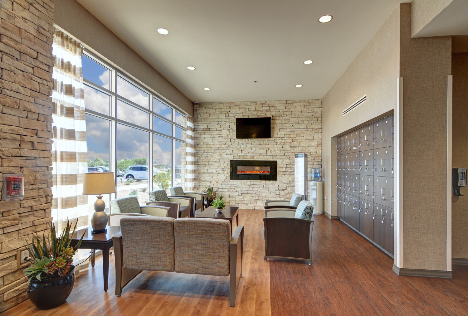 Lounge chairs and tables facing large windows and stone wall