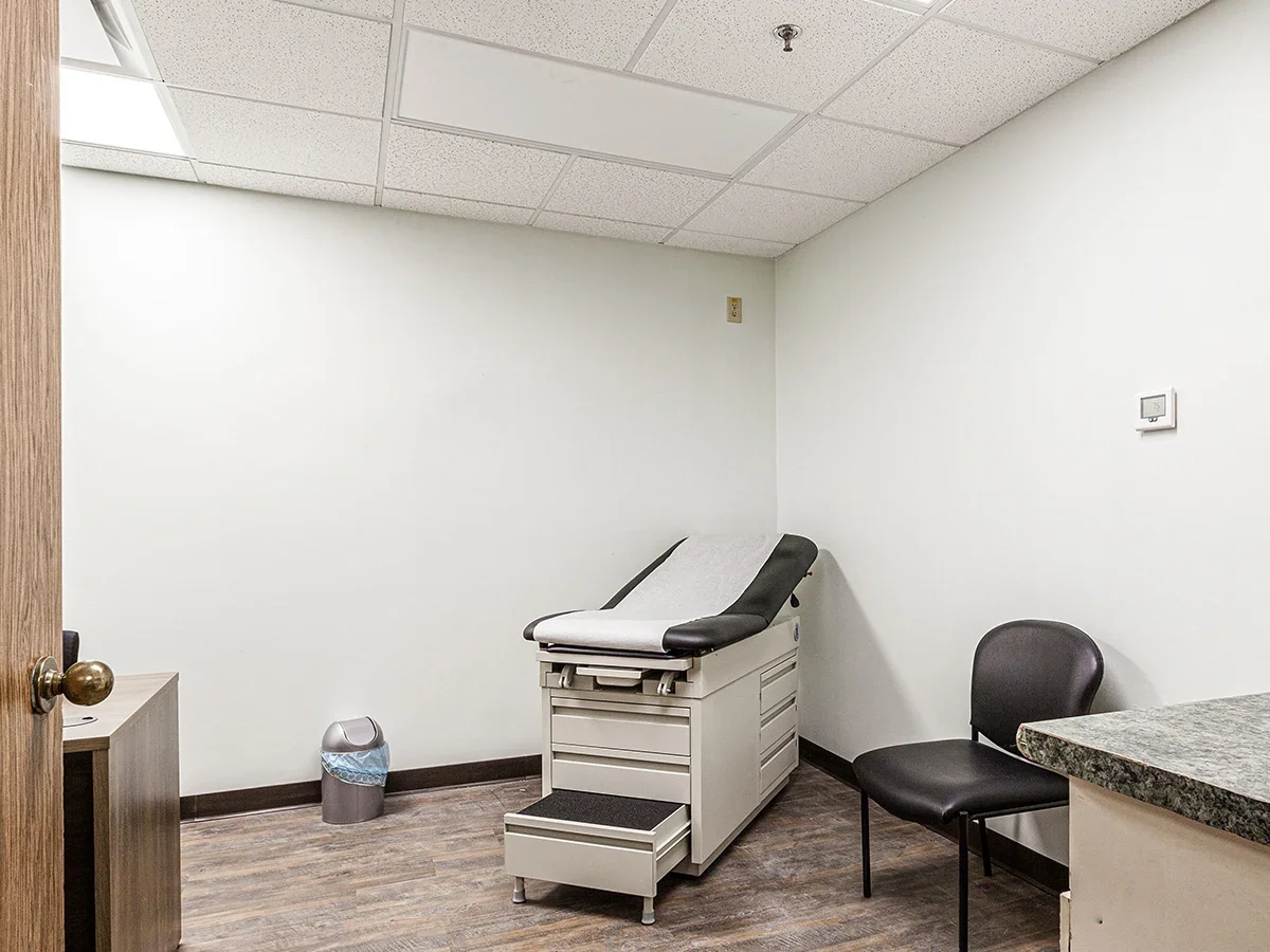 Medical exam room with patient bed, chair, and minimal furnishings