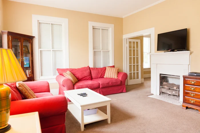 Cozy living room with red sofas and TV above fireplace
