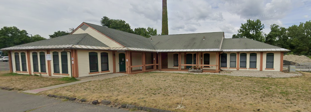 One-story beige building with green roof and front porch