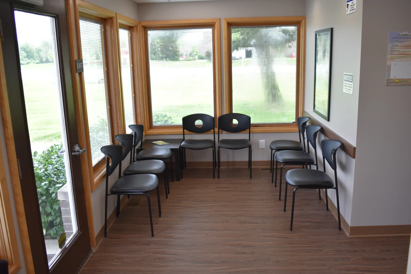 BrightView Health waiting area with black chairs arranged beside large windows and wood-look flooring