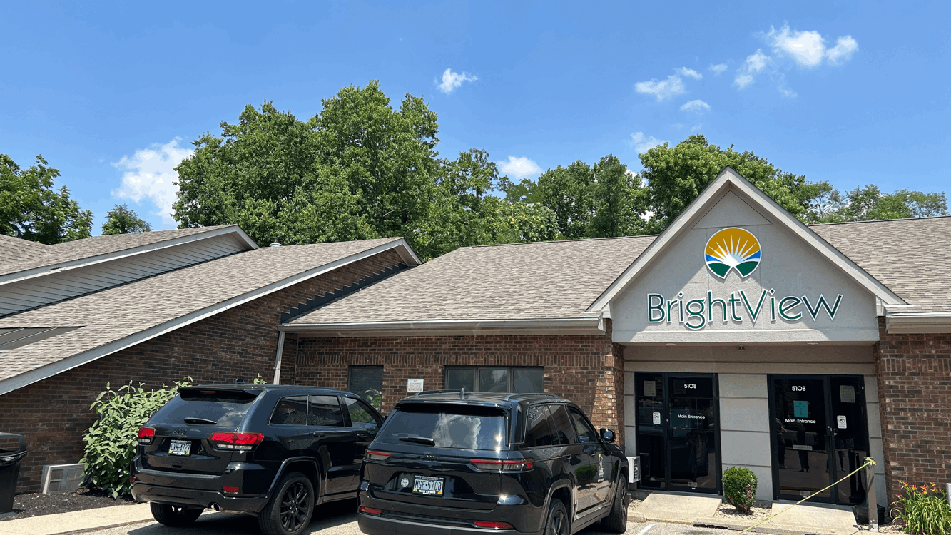 Exterior of BrightView Health Fairfield with brick facade, BrightView logo above the main entrance, parked vehicles, and trees under a blue sky