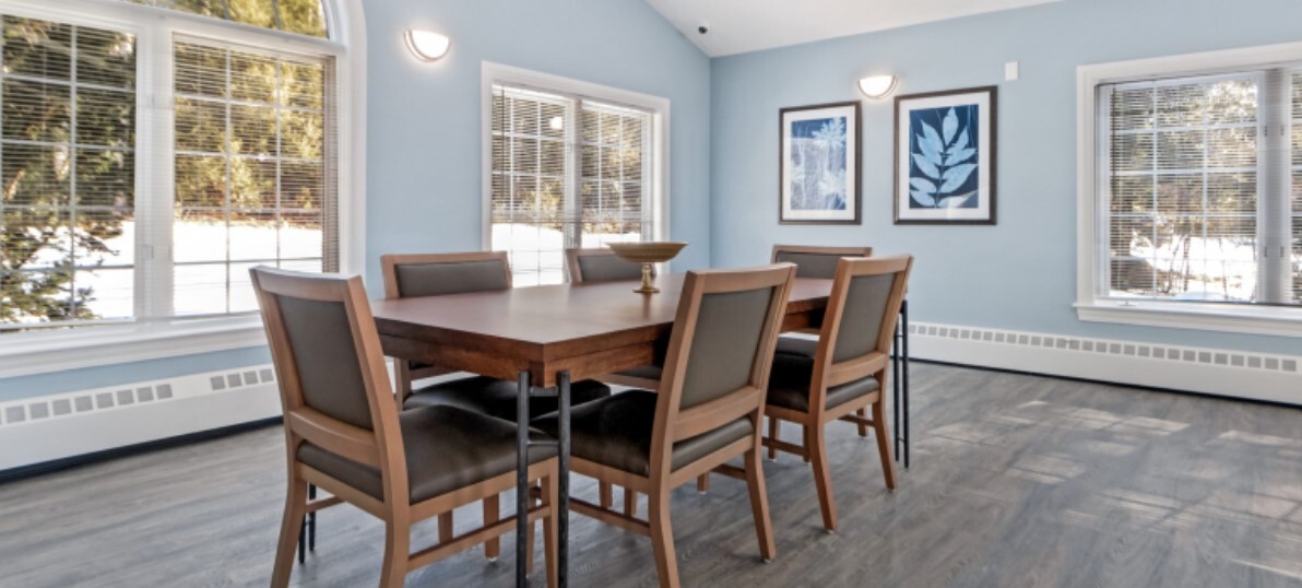 Dining area with chairs at a table and large windows.