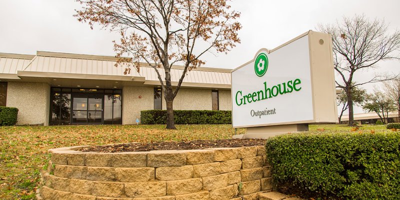  A modern outpatient facility with a welcoming sign and well-kept landscaping. The building is surrounded by trees and a calming environment.