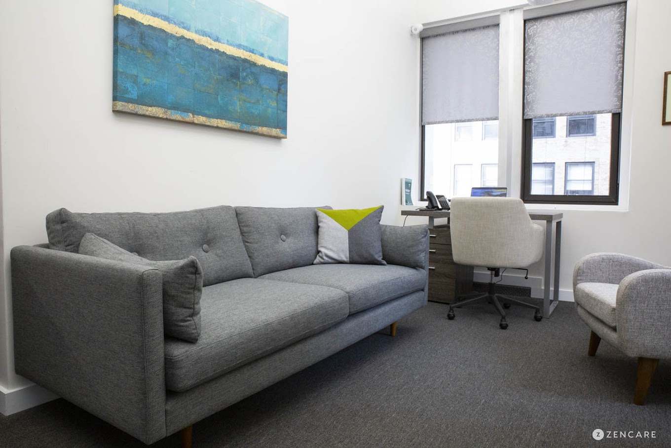 Office with gray couch and desk.