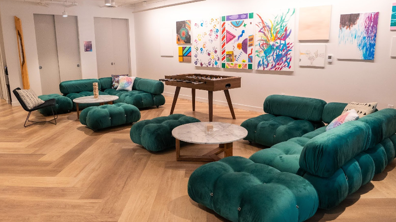 Lounge with green sofas, round tables, and colorful artwork