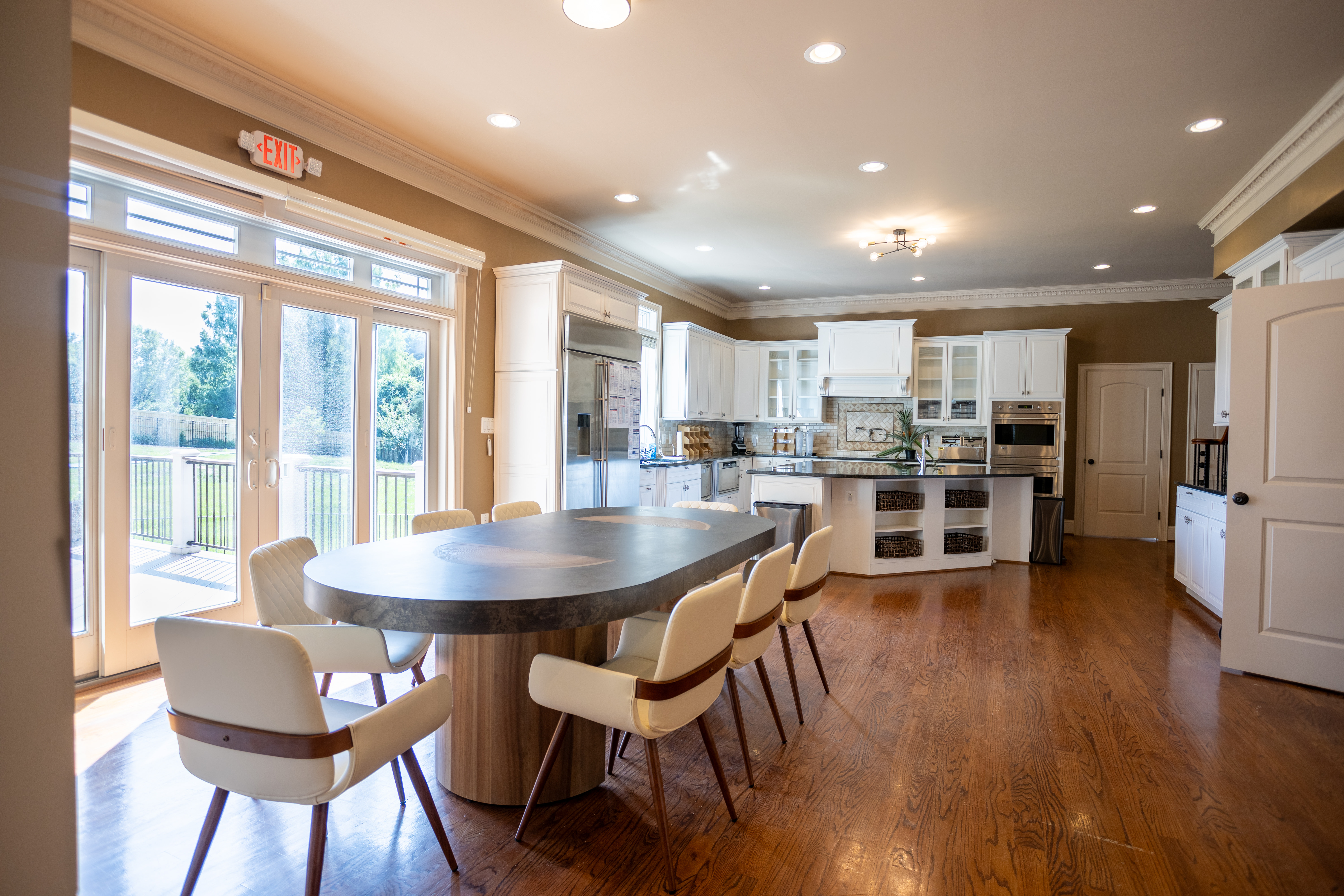 Kitchen with white cabinets and oval dining table near glass doors