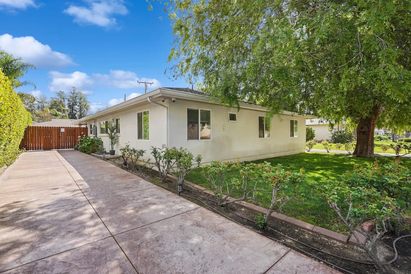 White building with trees and fenced driveway