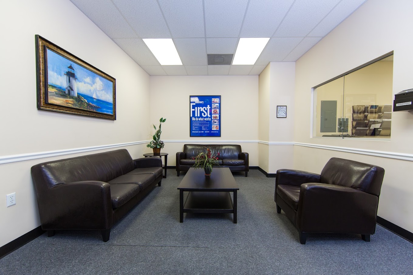 Lounge area with brown leather couches and framed wall art.