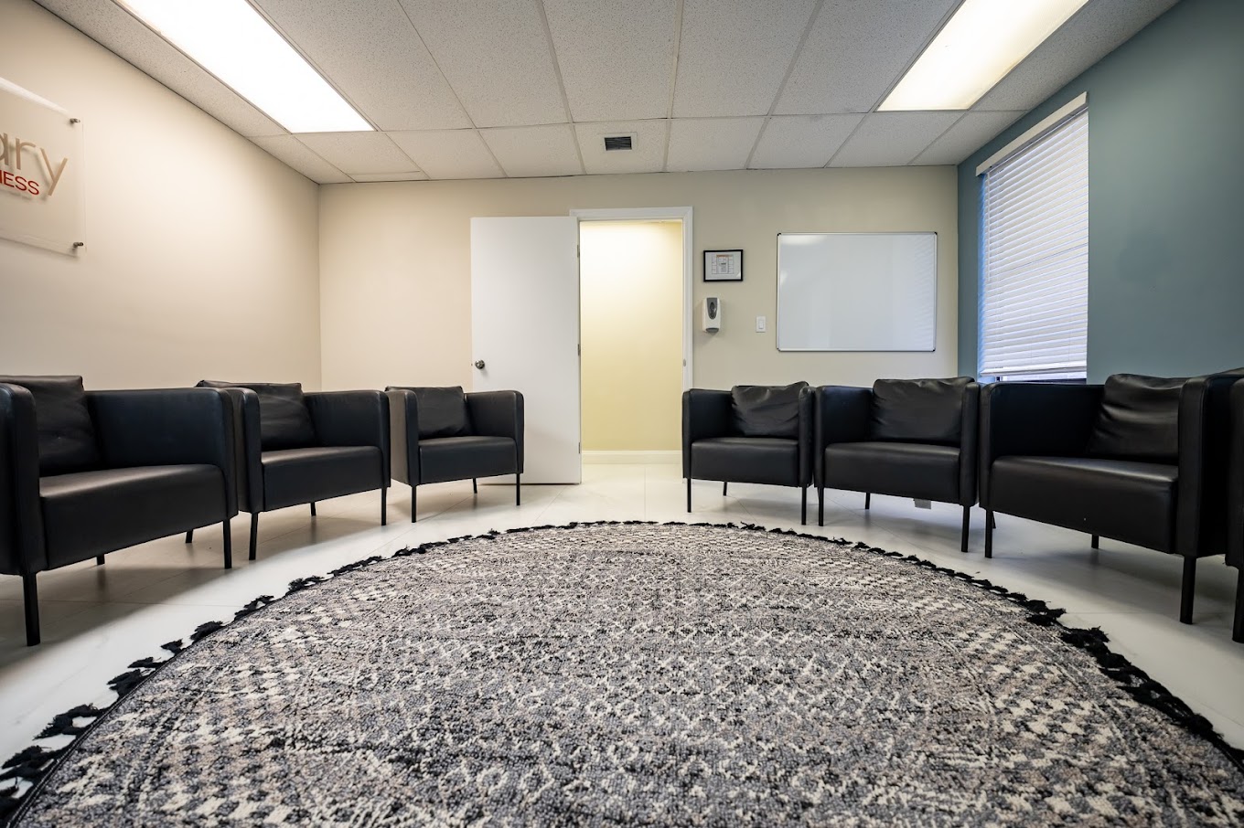 Circle of black chairs around a large patterned rug