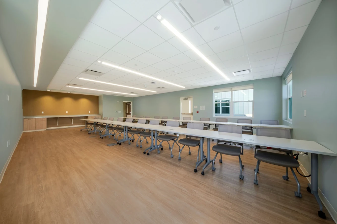 Spacious therapy and meeting room with long tables, rolling chairs, and large windows