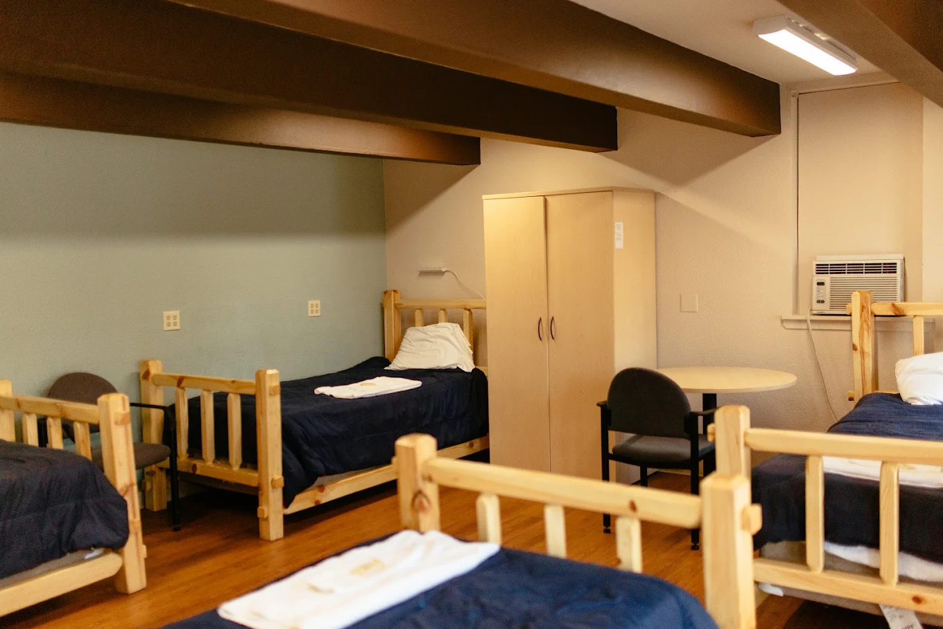 Shared bedroom with multiple single beds and AC unit