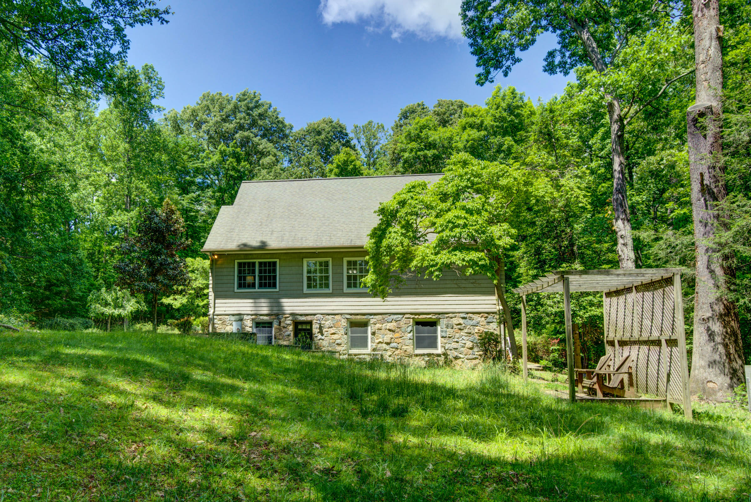 Wood and stone cabin surrounded by trees and greenery.