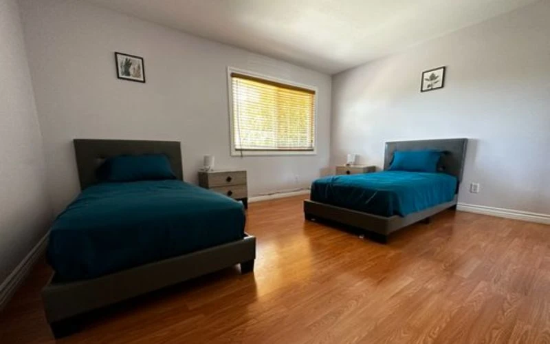 Two twin beds with teal bedding on wood floor