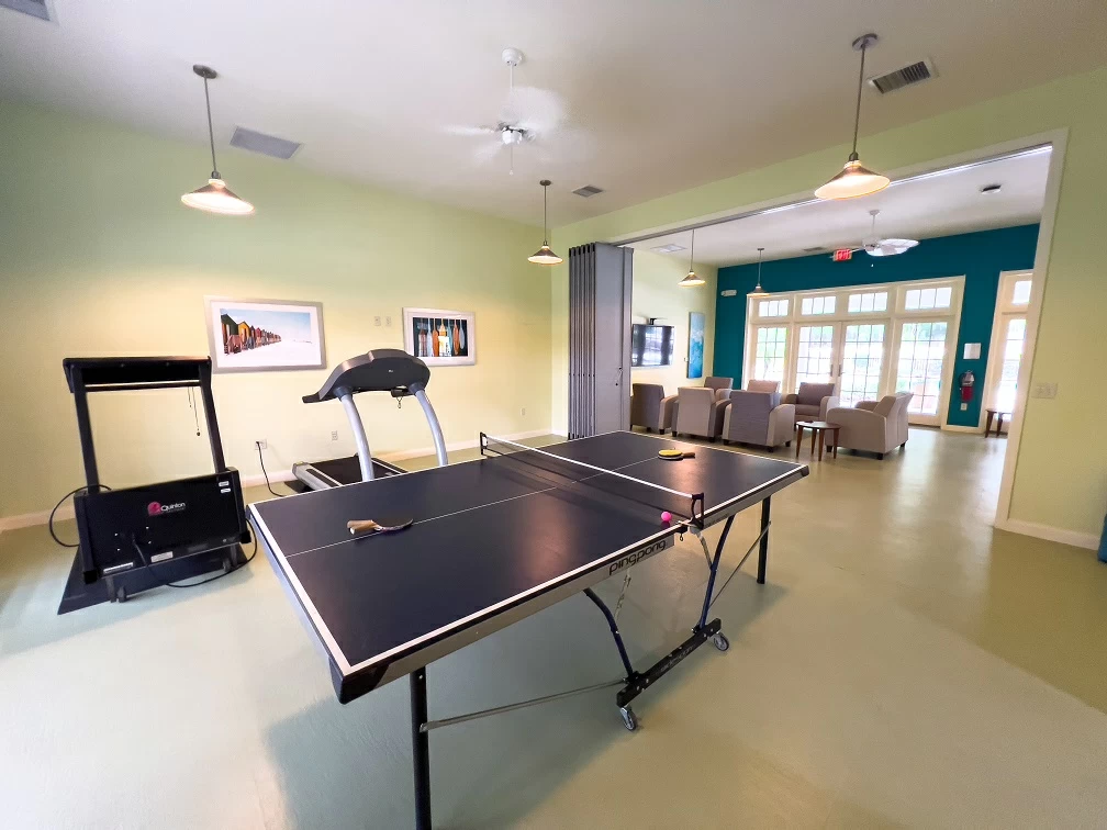 Recreational space with ping pong table, treadmill, lounge seating, and large windows