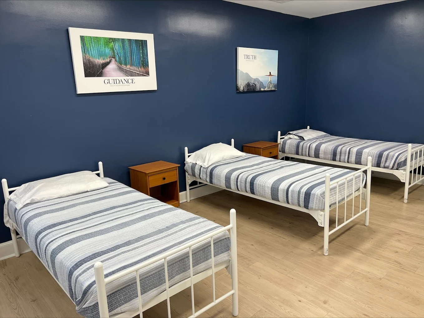 Three single beds in a blue-walled rehab bedroom