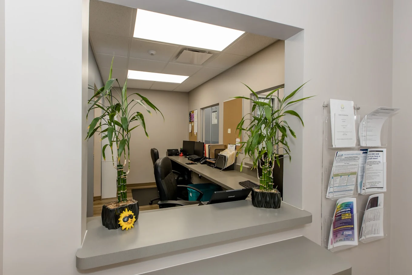 Check-in window with counter, office equipment, and plants