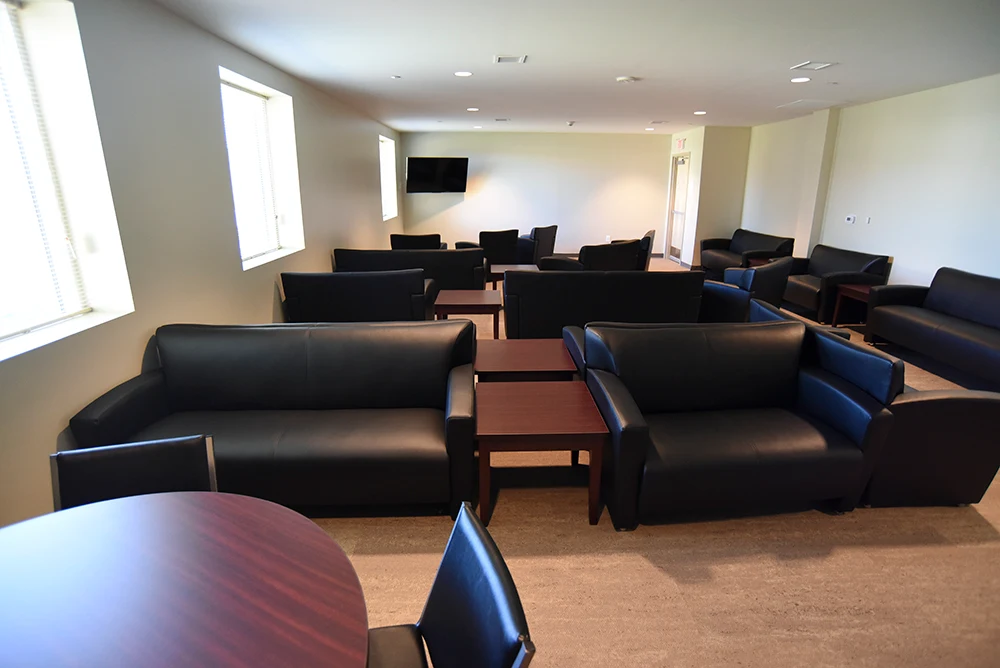 Spacious common lounge with black sofas, tables, and television