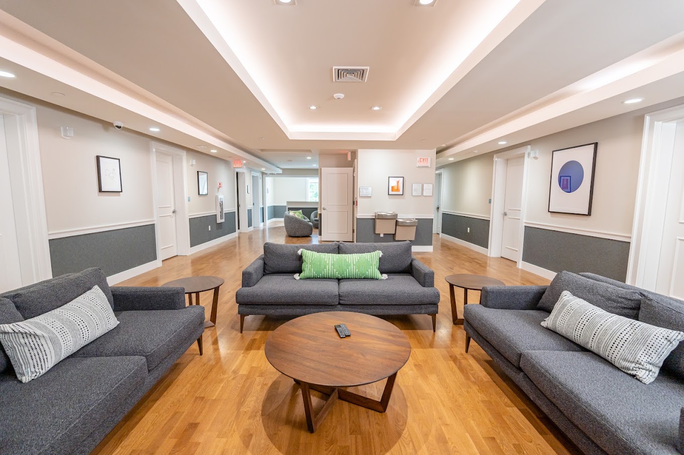 A spacious and cozy common area with large sectional sofas, bright accent pillows, and a wooden ceiling accent.