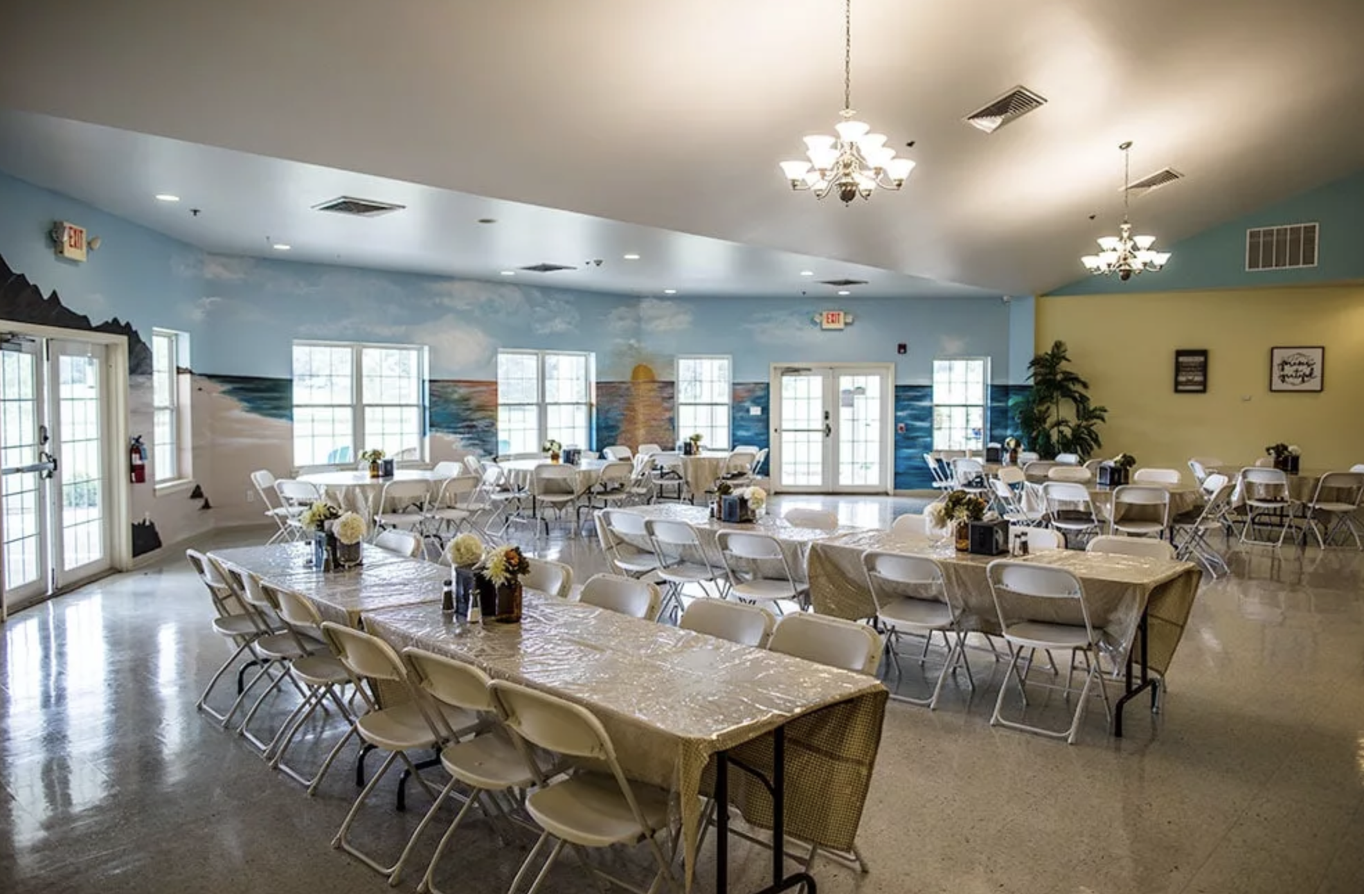 A spacious dining hall with tables, chairs, and a mural on the wall.
