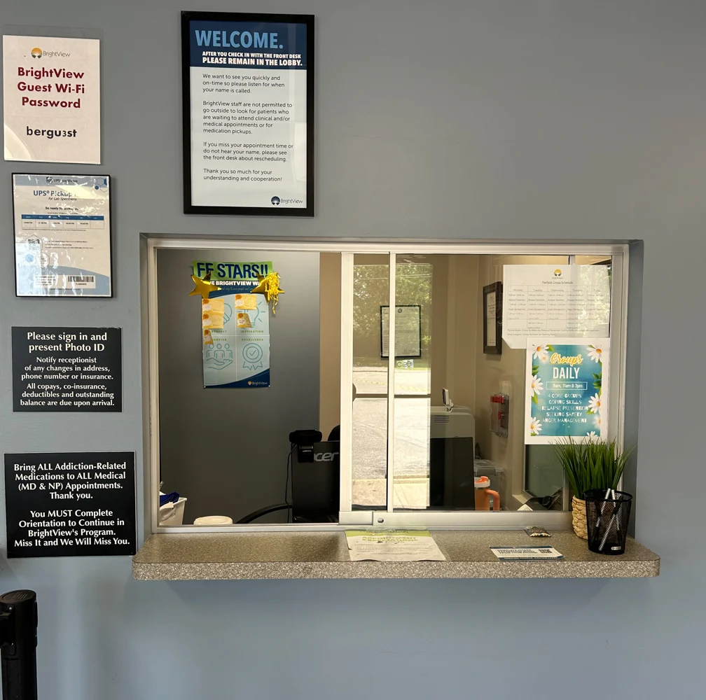 BrightView Health check-in window with reception counter, informational signs, computer workstation, and patient notices