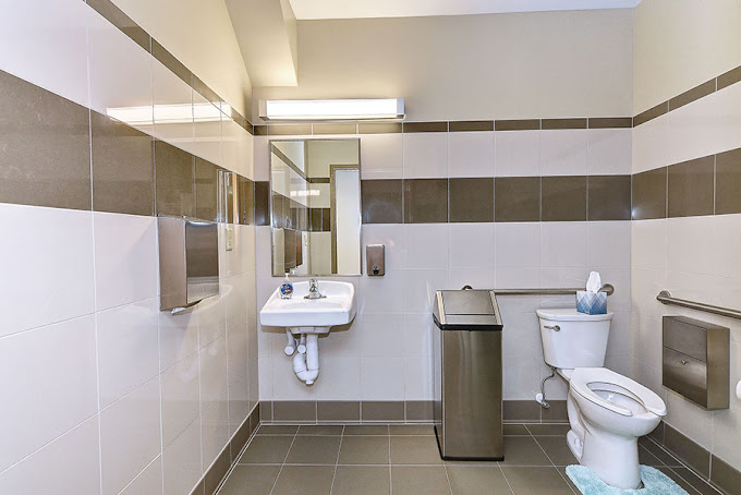 Modern bathroom with tile walls, sink, and accessible toilet.
