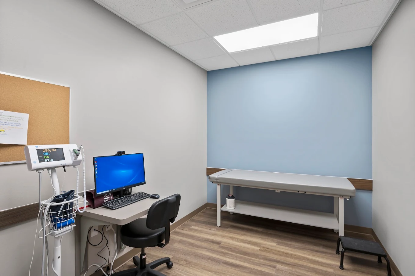 Exam room with examination table, vital-sign monitor, and computer workstation