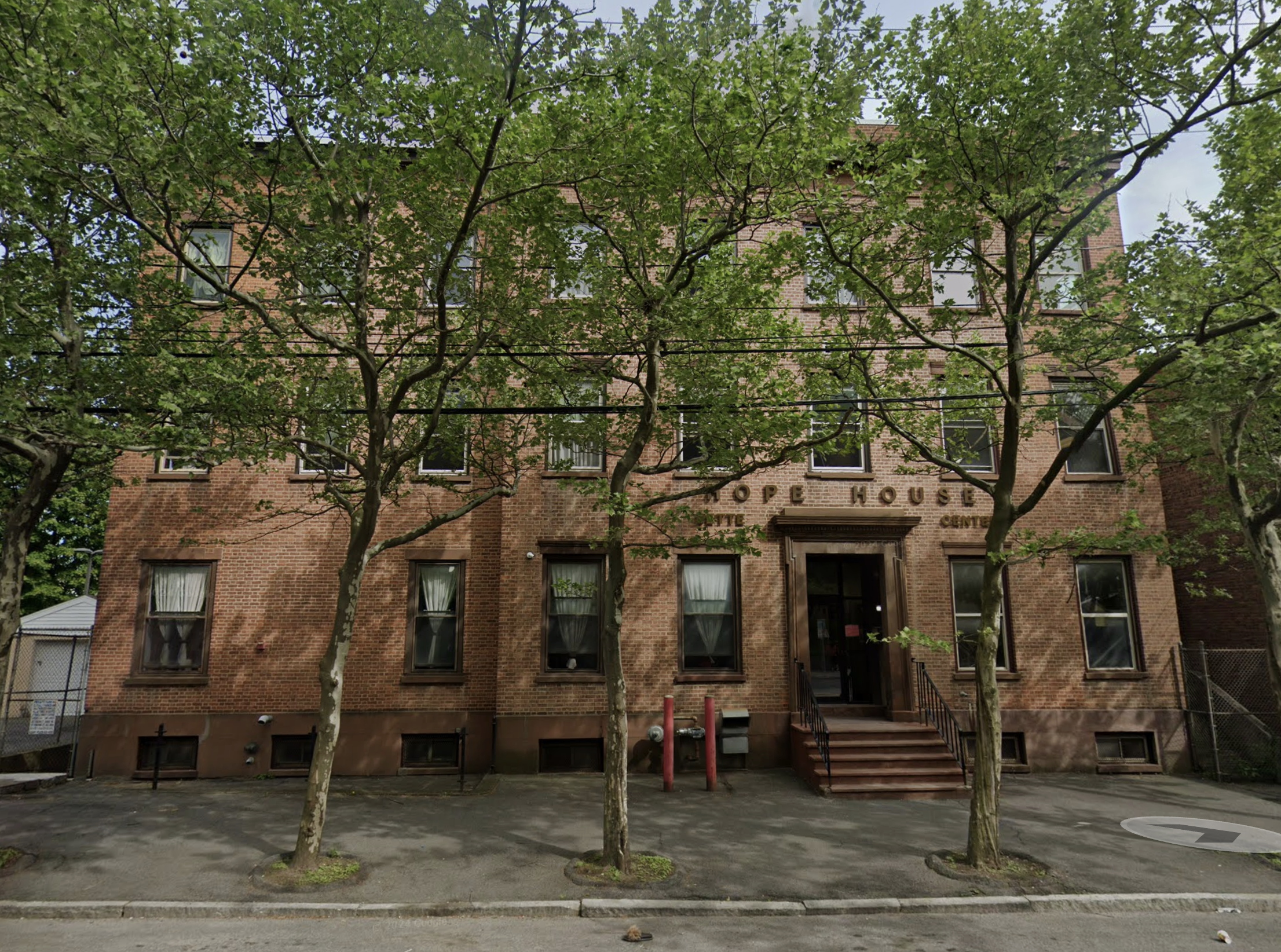 Brick building with front steps and trees lining the sidewalk