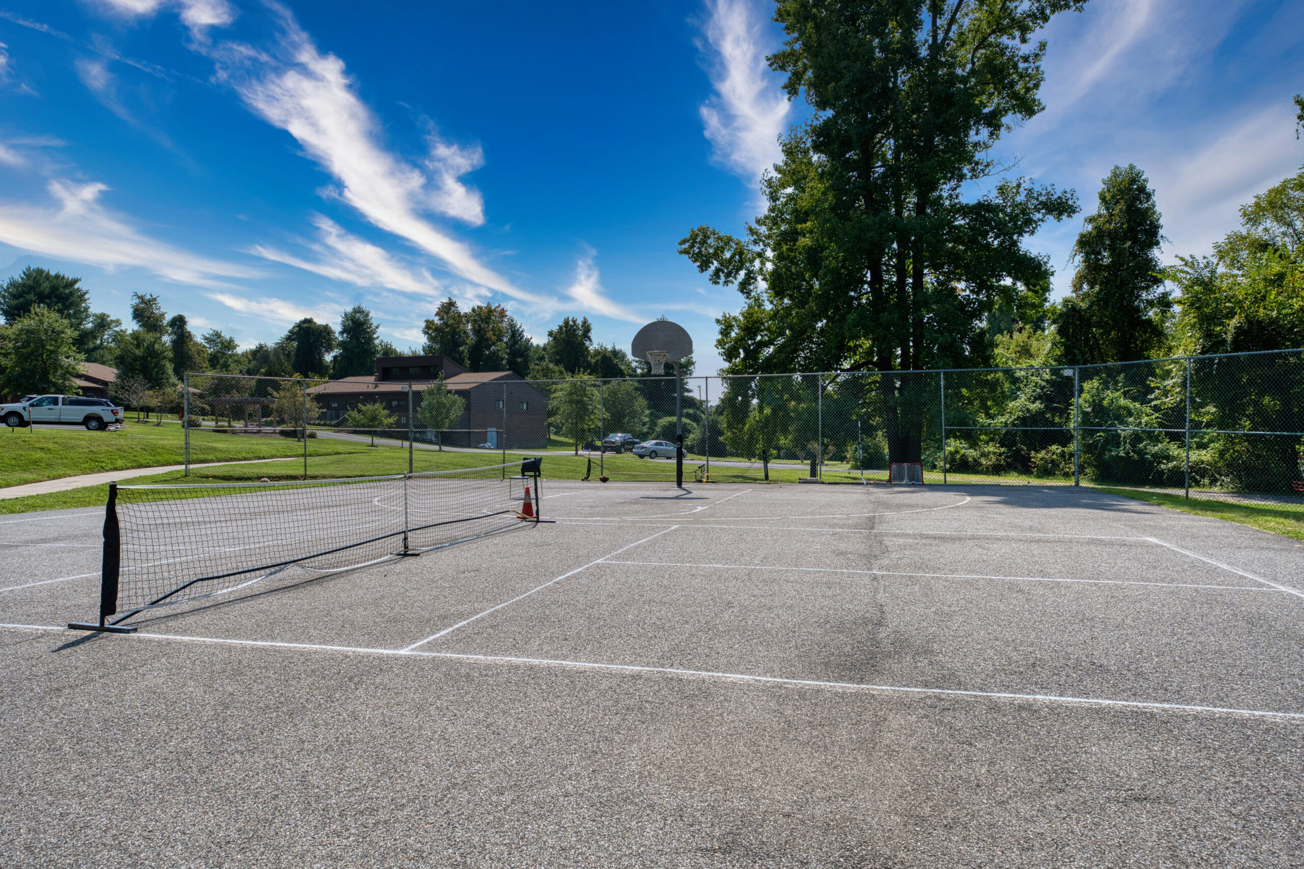 Outdoor court with tennis net and basketball hoop