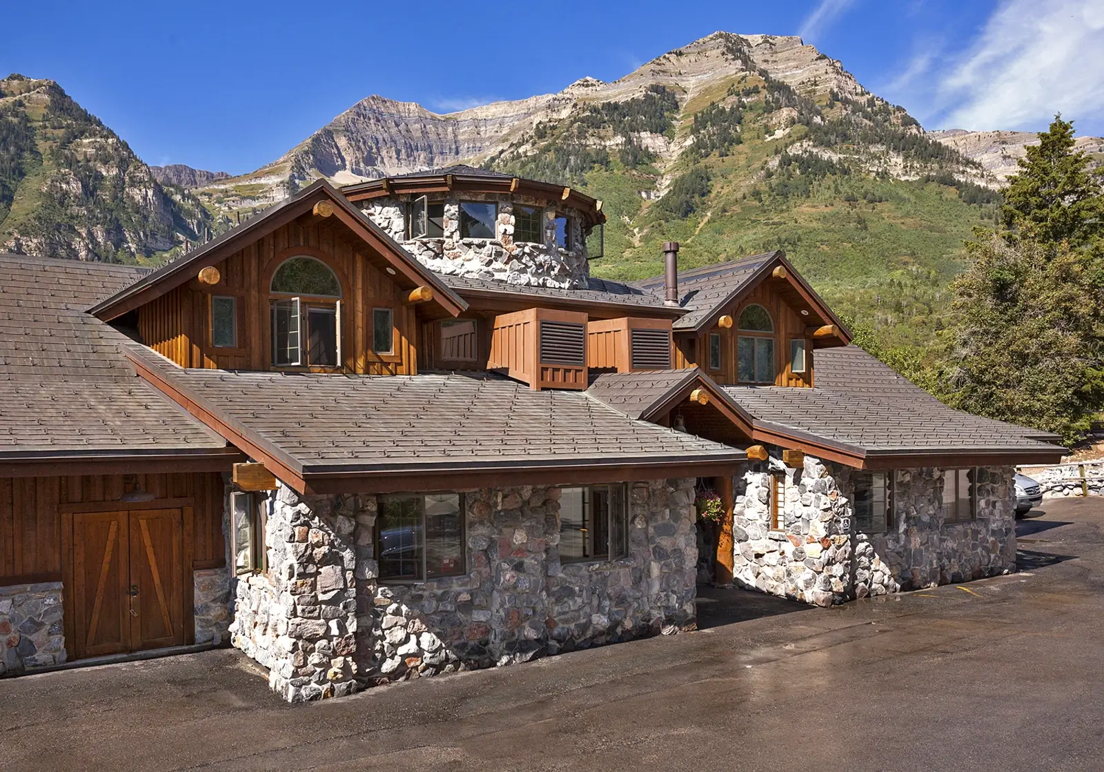 Lodge-style building with mountain backdrop and stone walls
