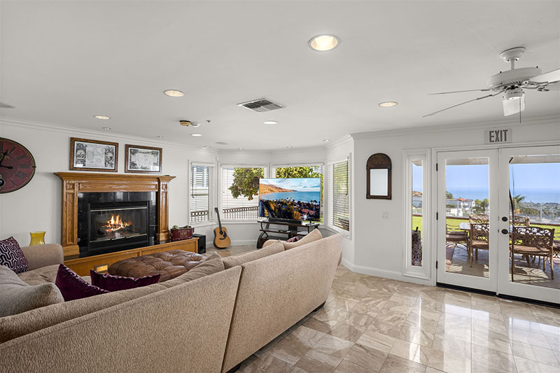 Cozy living room with fireplace, sectional couch, and ocean view.