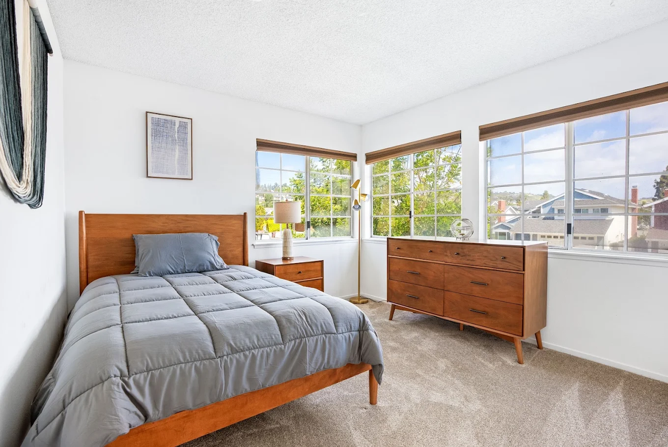 Private bedroom with single bed, dresser, and large windows