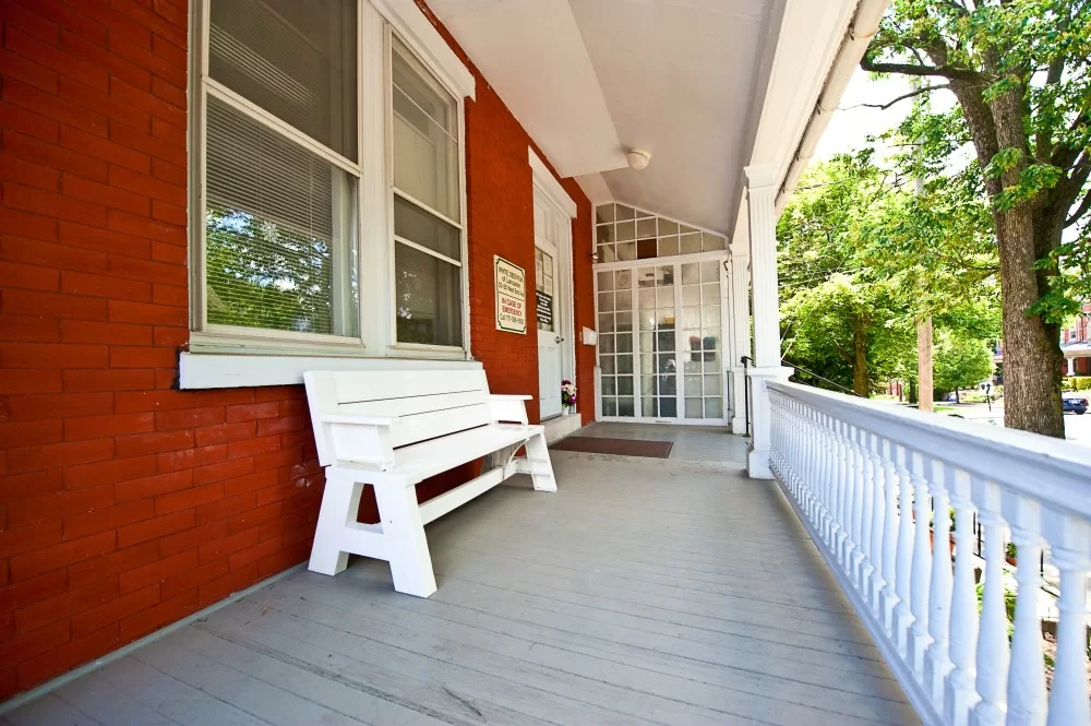 Covered porch with white bench and wooden railing