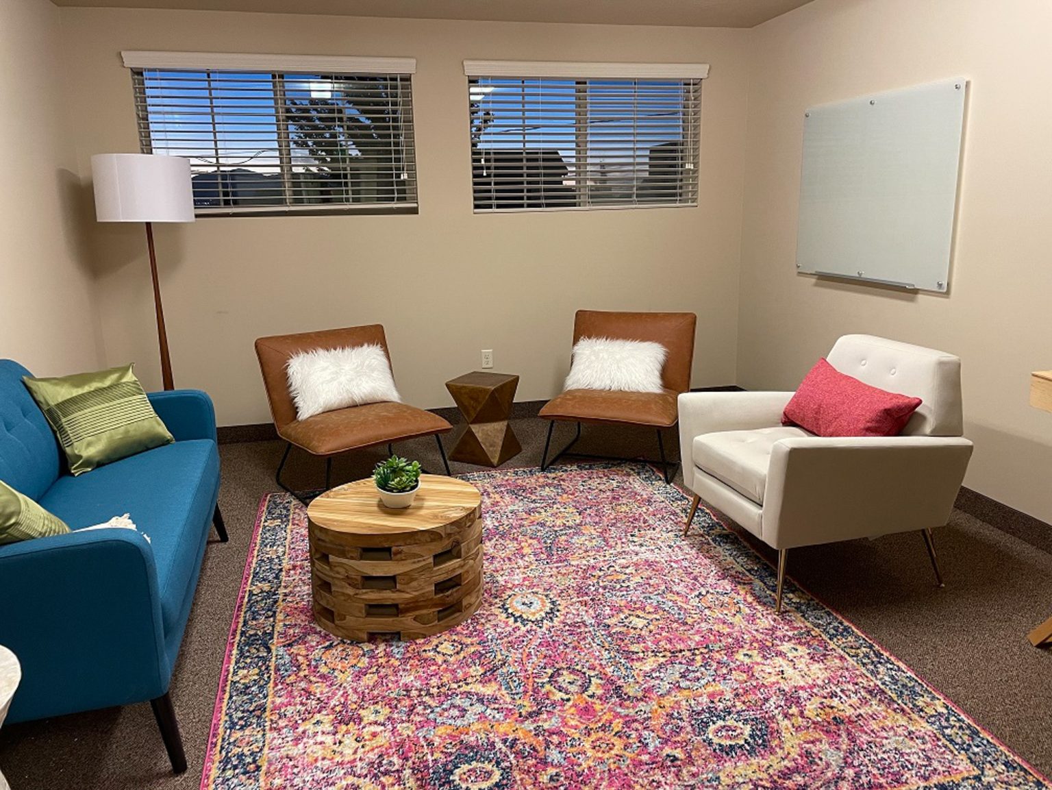 Cozy therapy room with sofa, chairs, and whiteboard